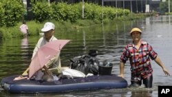 曼谷的市民10月23日在被洪水淹没的地区涉水而行