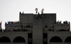 Demonstrators are seen on a building during a protest over corruption, lack of jobs and poor services, in Baghdad, Iraq Oct. 26, 2019.