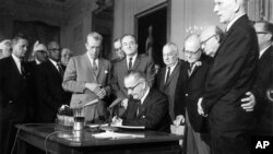 На этом архивном фото от 2 июля 1964 года президент Линдон Джонсон подписывает Закон о гражданских правах в Восточной комнате Белого дома в Вашингтоне (AP Photo, File).