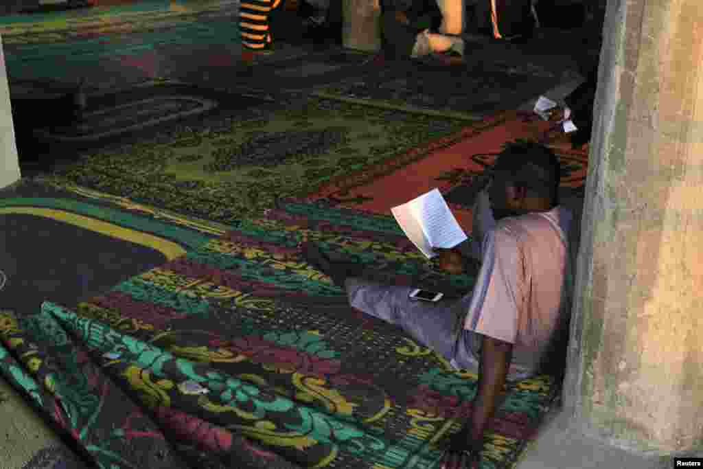 A man reads before breaking fast during the Islamic holy month of Ramadan at Nasfat Mosque in Utako, Abuja.