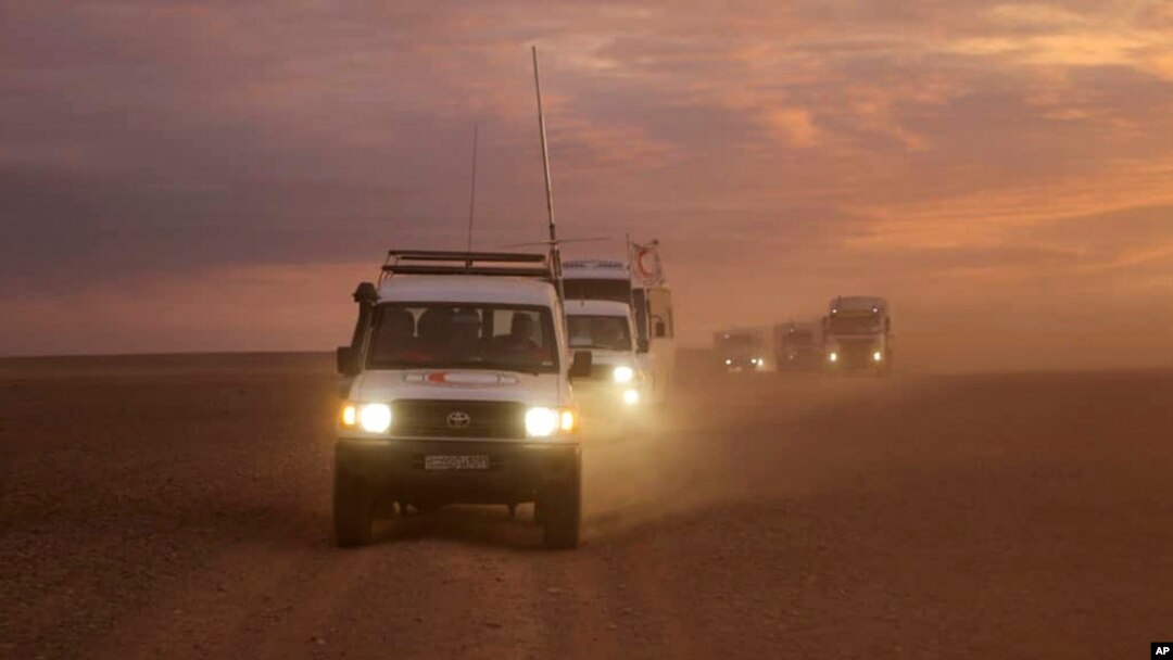 This photo released by the Syrian Arab Red Crescent, shows a convoy of vehicles of the Syrian Arab Red Crescent driving in the Syrian desert heading to Rukban camp between the Jordan and Syria borders, Nov. 4, 2018.