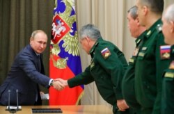 Russian President Vladimir Putin, left, shakes hands with military officials in the Bocharov Ruchei residence in the Black Sea resort of Sochi, Russia, Dec. 5, 2019.