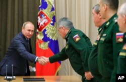 Russian President Vladimir Putin, left, shakes hands with military officials in the Bocharov Ruchei residence in the Black Sea resort of Sochi, Russia, Dec. 5, 2019.