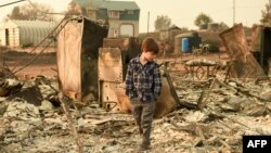 Jacob Saylors, 11, walks through the burned remains of his home in Paradise, California on November 18, 2018. The family lost a home in the same spot to a fire 10 years prior. 