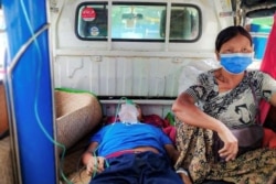 A relative sits with a COVID-19 patient being taken to hospital in the town of Kale, Sagaing region, Myanmar, July 6, 2021.