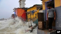 Seorang pria India berdiri di dekat rumahnya ketika gelombang yang disebabkan oleh pasang naik menghantam deretan rumah di tepi pantai Laut Arab, Mumbai, India, Rabu, 3 Juli 2019. 