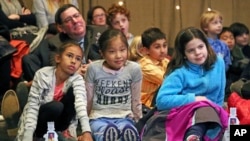 FILE -- Pittsburgh Mayor Bill Peduto, left rear, sits on the floor with a group of students from Oakland's Falk School during the first-day-of-issue dedication of the Mister Rogers Forever Stamp in WQED's Fred Rogers Studio in Pittsburgh, March 23, 2018.