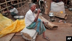 Trader smokes a cigarette as he waits for customers at a temporary cattle market for the upcoming Eid al-Adha festival in Dhaka, Bangladesh, Oct. 1, 2014.