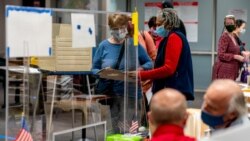 A poll worker helps a woman with her ballot in early voting at the Fairfax County Government Center, Sept. 18, 2020, in Fairfax, Virginia.