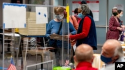 A poll worker helps a woman with her ballot in early voting at the Fairfax County Government Center, Sept. 18, 2020, in Fairfax, Virginia.