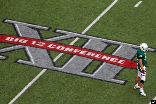 FILE - Baylor's Matt Ritchey stands by the Big 12 Conference logo on the field during the team's NCAA college football game against TCU in Waco, Texas, Oct. 13, 2012. (AP Photo/Tony Gutierrez, File)