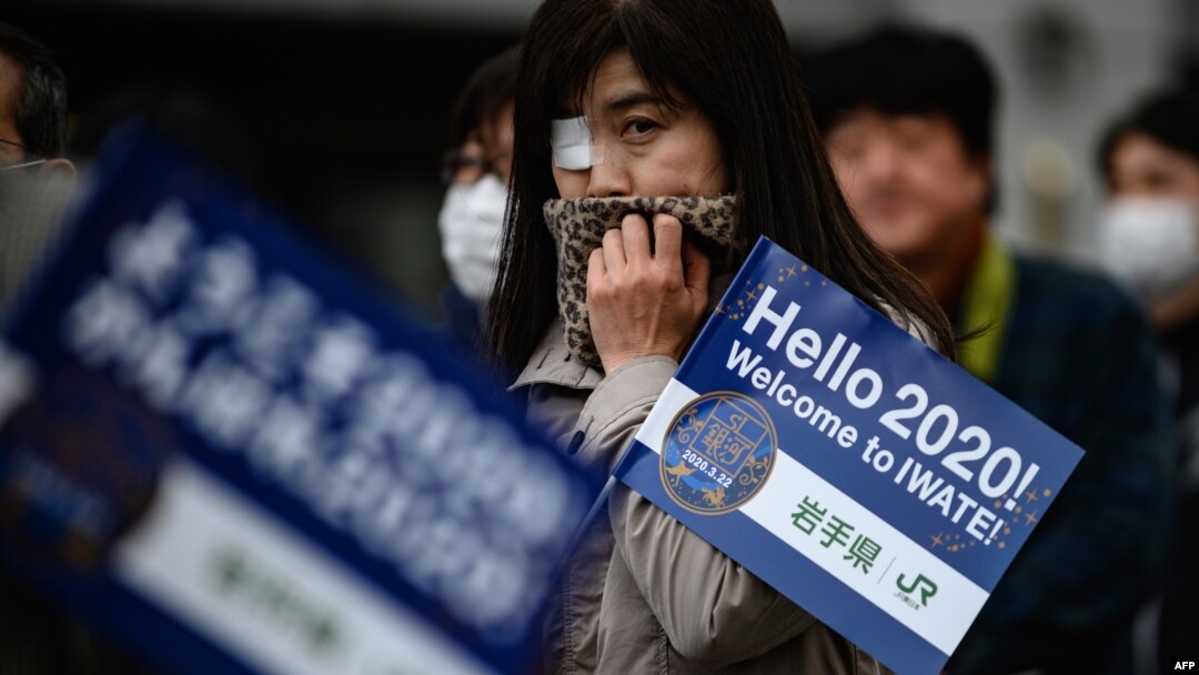 People queue to see the Tokyo 2020 Olympic flame on display outside the railway station in Tono, Iwate prefecture, March 22, 2020.