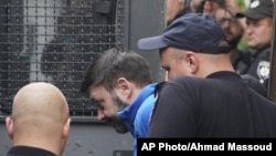 Kirill Vyshinskiy, pimpinan kantor Ukraina di RIA Novosti (kantor berita Rusia) di Ukraina, dikawal dari ruang pengadilan di Kiev, Ukraina, 15 Juli 2019.