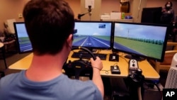 Tate Ellwood-Mielewski test drives on a simulator as part of a study at the University of Michigan, Friday, April 29, 2022, in Ann Arbor, Michigan. (AP Photo/Carlos Osorio)
