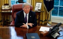 FILE - President Donald Trump sits over documents at his desk in the Oval Office of the White House, in Washington, Jan. 23, 2018.