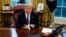 FILE - President Donald Trump sits over documents at his desk in the Oval Office of the White House, in Washington, Jan. 23, 2018. 