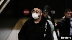 Seorang penumpang mengenakan masker tiba dengan penerbangan langsung dari China di Bandara Tacoma, Seattle, AS, 23 Januari 2020. (Foto: Reuters)