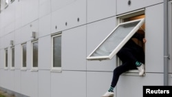 FILE - A resident climbs through a window at Kaershovedgaard, a former prison and now a departure center for rejected asylum seekers in Jutland, Denmark, March 26, 2019.