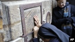 Una mujer ora frente a las puertas cerradas de la Iglesia del Santo Sepulcro, lugar donde los cristianos creen que fue el sitio de la crucifixión de Jesús, en Jerusalén, el martes, 27 de febrero de 2018.