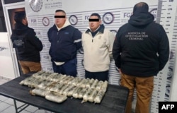 A photo released on Jan. 31, 2025, shows two suspects being presented with confiscated illegal drugs at an undisclosed location in Mexico. The Mexican government announced that day it had seized 18 kilos of fentanyl hidden in a bus.(Mexican Ministry of Defense and Navy via AFP)