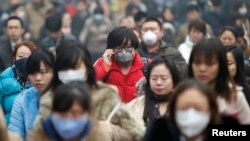 Peatones usando máscaras para protegerse de la contaminación en Beijín. El crecimiento poblacional debe tener un límite dicen las autoridades de la ciudad.