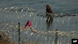 Un migrante camina hacia la frontera de Estados Unidos bordeada de alambre de púas, el lunes 31 de julio de 2023, cerca de Eagle Pass, en Texas. 