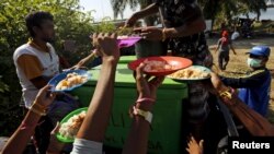 ເຮືອຊາວອົບພະຍົບ ບັງກລາແດັສ ທີ່ໄດ້ໄປເຖິງຝັ່ງ ອິນໂດເນເຊຍ ເມື່ອບໍ່ດົນມານີ້ ຍົກຈານຂອງພວກເຂົາຂຶ້ນ ເພື່ອຂໍເອົາອາຫານຕື່ມອີກ ຂະນະທີ່ ບໍລິການອາຫານເຊົ້າ ຢູ່ທີ່ພັກພາອາໄສ ໃນເມືອງ Kuala Langsa ຂອງແຂວງ Aceh ປະເທດອິນໂດເນເຊຍ, ວັນທີ 19 ພຶດສະພາ 2015. 