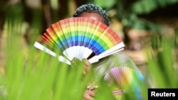 FILE - Quin Karala, 29, a member of LGBTQ community poses for a picture with rainbow colors at the offices of Rella Women's Empowerment Program, for LGBTQ rights advocacy in the Kulambiro suburb of Kampala, Uganda, April 4, 2023.