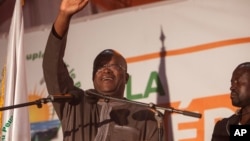 Newly elected president of Burkina Faso, Roch Marc Christian Kabore, waves at supporters after preliminary results showed him to be the winner of recent elections, supporters gather outside his campaign headquarters in Ouagadougou, Burkina Faso, Dec. 1, 2015.