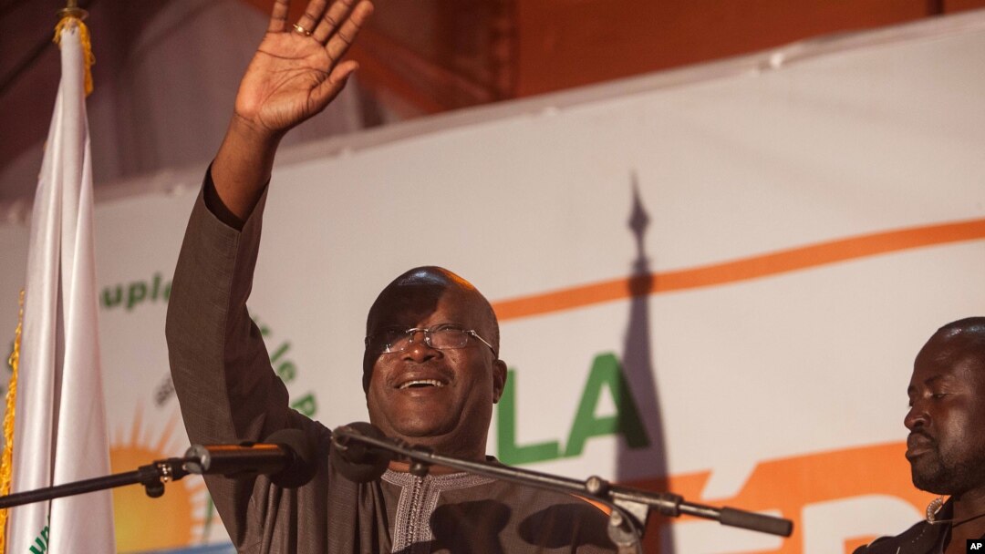 Newly elected president of Burkina Faso, Roch Marc Christian Kaboré, waves at supporters after preliminary results showed him to be the winner of recent elections, supporters gather outside his campaign headquarters in Ouagadougou, Dec. 1, 2015.