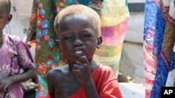 FILE - In this Dec. 17, 2020, photo, 3-year-old Peter Sebit stands outside a health clinic in Pibor, South Sudan, waiting to get food supplements.