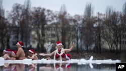 Para anggota kelompok Berlin Seals menggelar tradisi tahunan mereka merayakan Natal dengan terjun ke dalam sungai Oranke yang bekudi Berlin, Jerman, 25 Desember 2012. (AP Photo/Markus Schreiber)