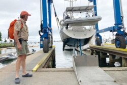 Robin Berthet, de Sheffield, Massachusetts, observa cómo su velero es arrastrado fuera del agua a tierra firme antes de la esperada tormenta, el viernes 20 de agosto de 2021, en Plymouth, Massachusetts, EE. UU.