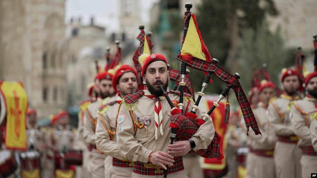 Anggota band pramuka Palestina berparade melalui Manger Square di Gereja Kelahiran, yang secara tradisional diyakini sebagai tempat kelahiran Yesus Kristus, selama perayaan Natal, di kota Betlehem, Tepi Barat, Jumat, 24 Desember 2021. (Foto: AP)
