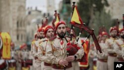 Anggota band pramuka Palestina berparade melalui Manger Square di Gereja Kelahiran, yang secara tradisional diyakini sebagai tempat kelahiran Yesus Kristus, selama perayaan Natal, di kota Betlehem, Tepi Barat, Jumat, 24 Desember 2021. (Foto: AP)