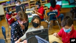 ARCHIVO - La maestra de jardín de infantes Karen Drolet, izquierda, trabaja con un estudiante en Raíces Dual Language Academy, una escuela pública en Central Falls, Rhode Island, el 9 de febrero de 2022.