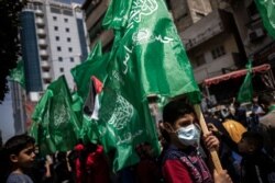 Palestinians hold Hamas flags as they protest in solidarity with Muslim worshippers in Jerusalem, in Gaza City, April. 23, 2021.