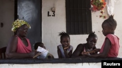 A grandmother gives her grandchildren school lessons on their porch in Sierra Leone's capital Freetown, April 24, 2012.