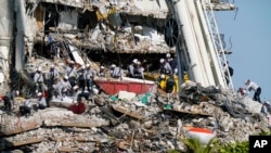 Workers search the rubble at the Champlain Towers South Condo, June 28, 2021, in Surfside, Fla. where many people were still unaccounted for after Thursday's fatal collapse.