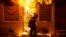A firefighter uses a saw to open a metal gate while fighting a fire in a convenience store and residence during clashes after the funeral of Freddie Gray in Baltimore, Maryland, April 28, 2015. 