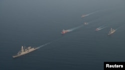 Military vessels escort tugboats as they sail toward the damaged oil tanker Sounion, which has been on fire since Aug. 23, after an attack by Houthi militants, on the Red Sea, Sept. 14, 2024. (Eunavfor Aspides via Reuters)