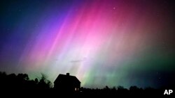 FILE - The northern lights flare in the sky over a farmhouse, late Friday, May 10, 2024, in Brunswick, Maine. 