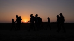 ARCHIVO - Empieza a amanecer mientras familias migrantes, provenientes de Honduras y El Salvador y que buscan asilo en Estados Unidos, caminan hacia el muro fronterizo tras cruzar el Río Grande, en Peñitas, Texas, el 26 de marzo de 2021.