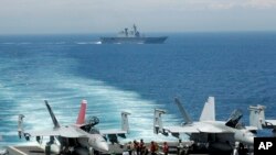 Aviones caza de EE.UU. se preparan para despegar del portaaviones nuclear George Washington, mientras un barco de guerra surcoreano pasa cerca durante maniobras militares de los dos países en el Mar del Este frente a la costa surcoreana. Foto de archivo.