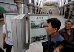 FILE - Men read public newspapers with headlines featuring the news on the country's rocket launcher test at a subway station in Pyongyang, North Korea, Sept. 11, 2019.