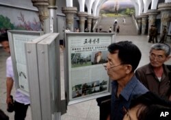 FILE - Men read public newspapers with headlines featuring the news on the country's rocket launcher test at a subway station in Pyongyang, North Korea, Sept. 11, 2019.