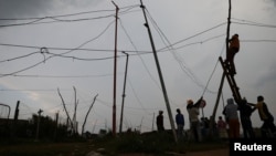 FILE: Locals use a makeshift stepladder as they illegally connect electricity from Eskom's power supply at Motsoaledi, an informal settlement within Soweto, in South Africa. Taken 1.18.2022