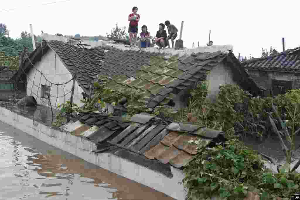 Residents wait on the roof of a flooded building in Anju City, South Phyongan Province, North Korea, July 30, 2012.