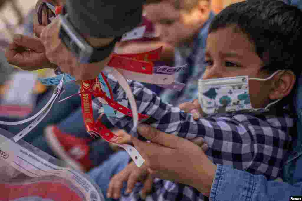 A U.S. Border Patrol Agent removes a wristband from Santiago, a 4-year-old asylum-seeking migrant boy from Honduras, after he crossed the Rio Grande River into the U.S. from Mexico with his mother, in Penitas, Texas, March 9, 2021.
