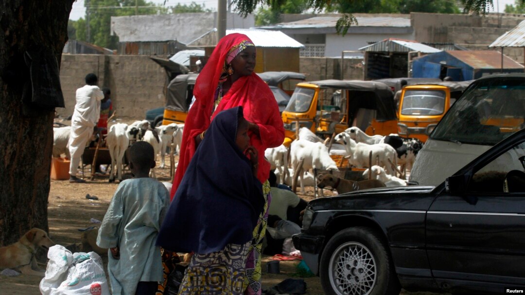 Seorang perempuan membawa 2 anaknya di jalanan antara Jos-Maiduguri, di mana militer Nigeria mengumumkan diberlakukannya jam malam (19/5).
